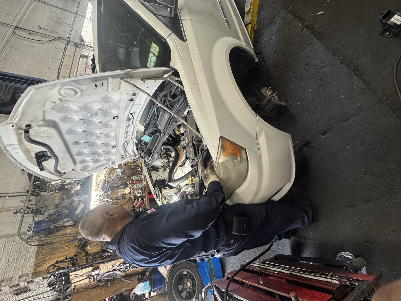 Mechanic performing engine repair with hood open